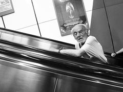 Alter Mann auf Rolltreppe